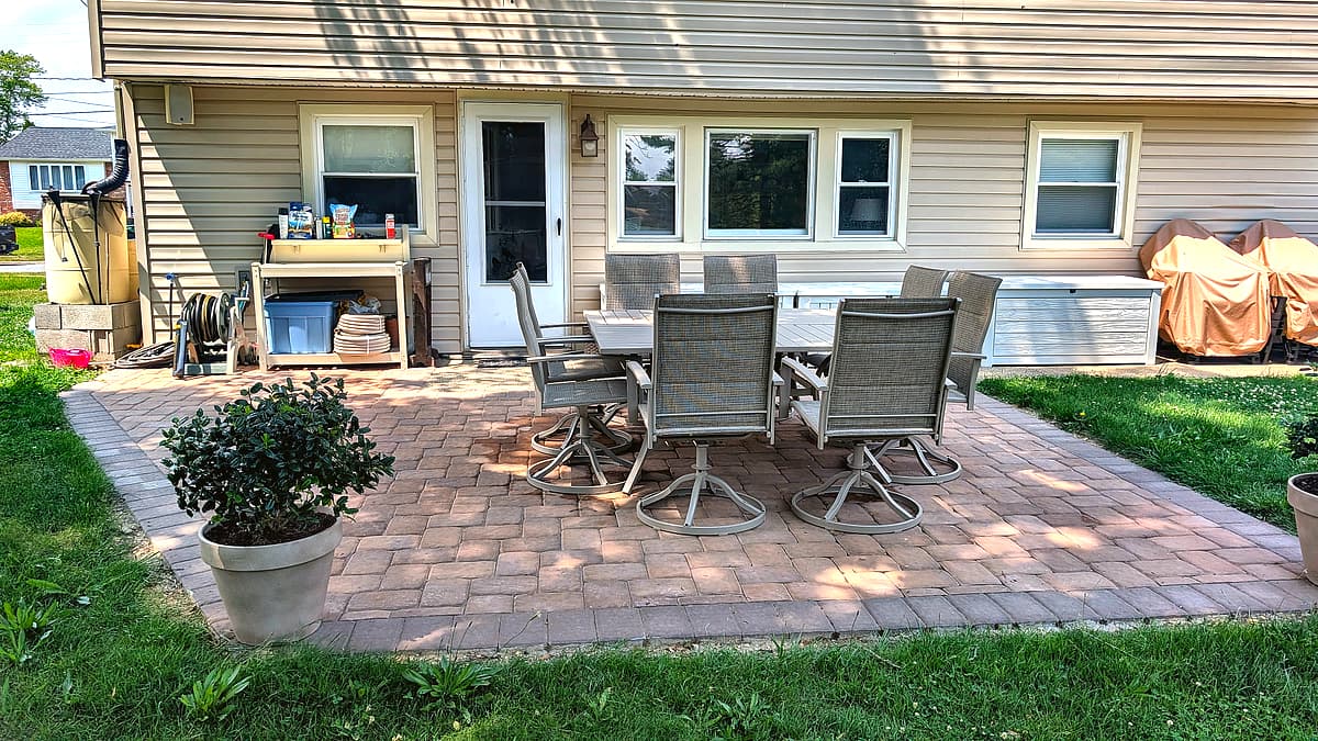 Wide paver patio with potted plants and outdoor furniture
