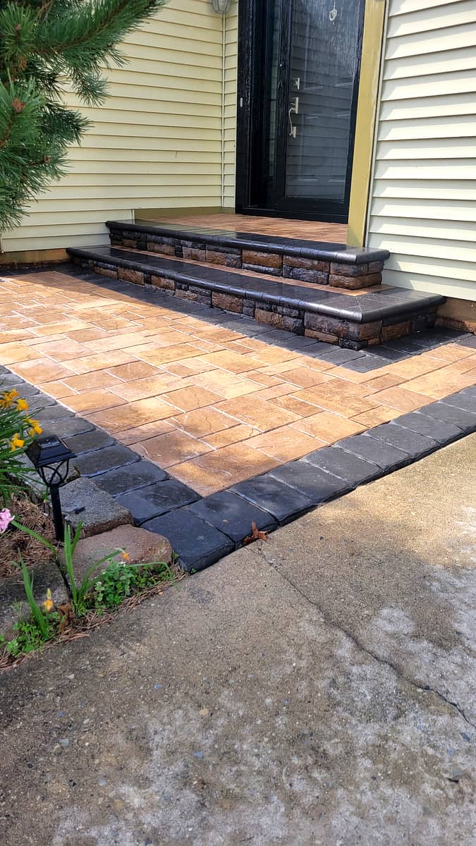 Front entry rebuilt in tan pavers with charcoal border and stone-faced steps