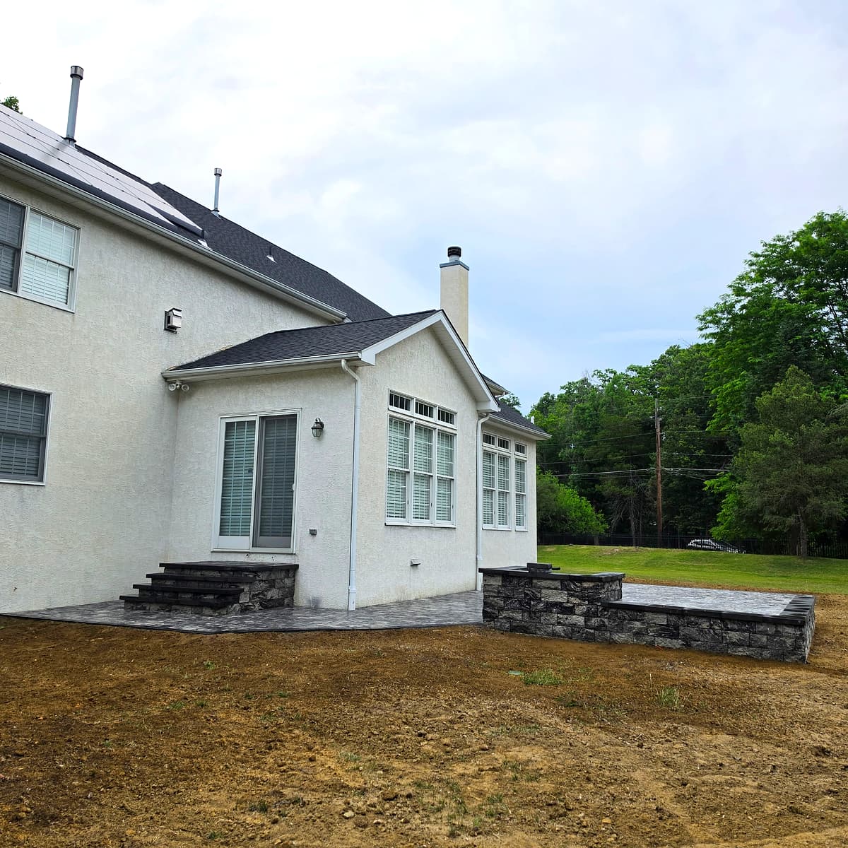 Backyard paver patio with stone seat wall