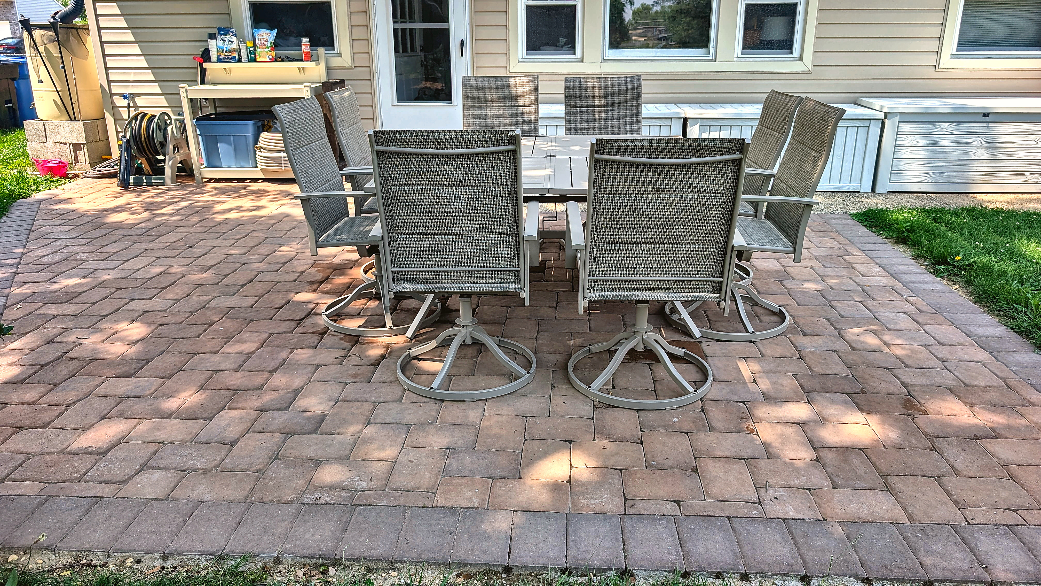 Paver patio with eight-seat outdoor table set against the back of the house