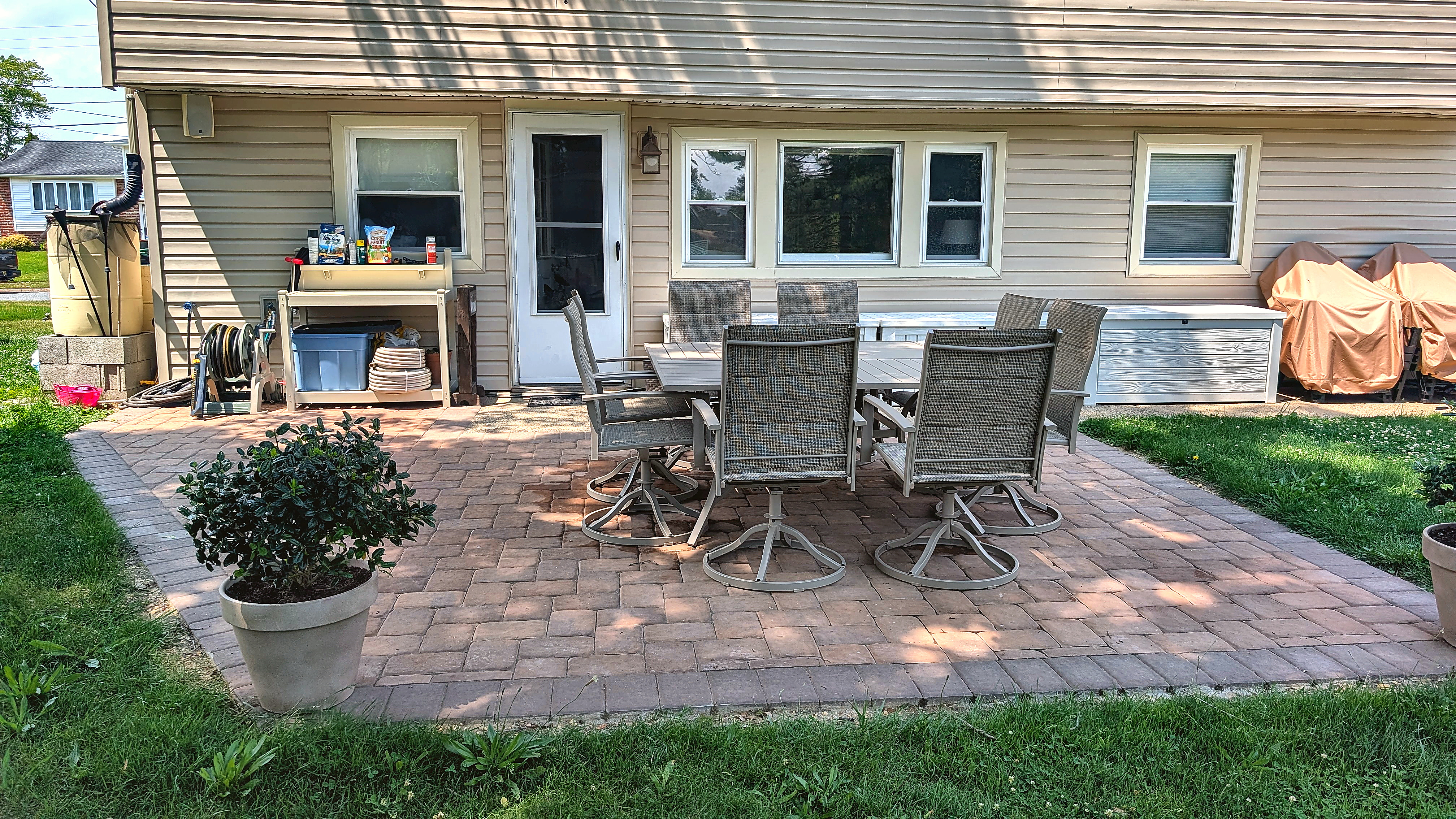 Wide paver patio with potted plants and outdoor furniture